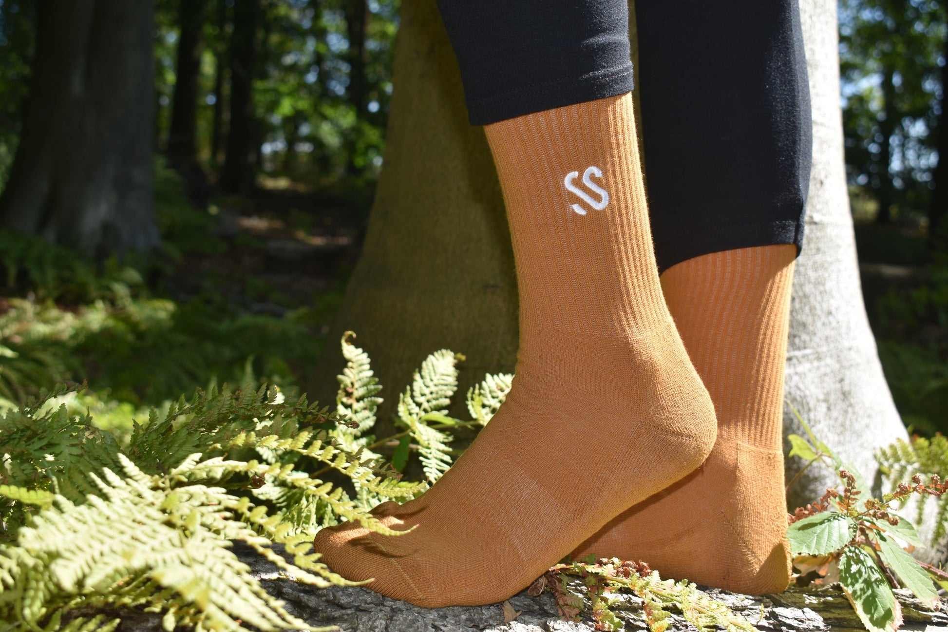 A pair of autumnal gold crew socks in the forest