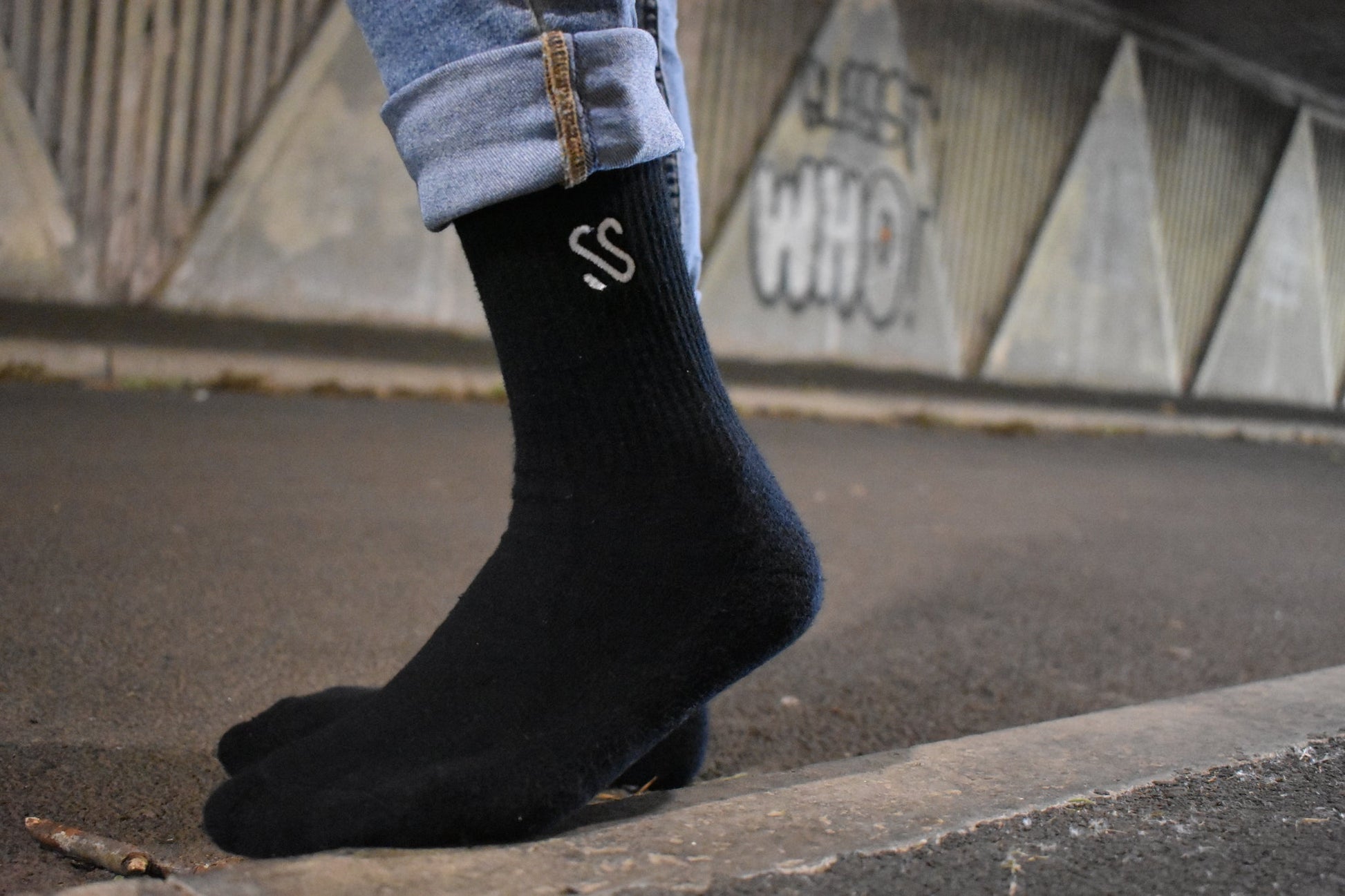 A pair of black crew length combed cotton socks being worn outside