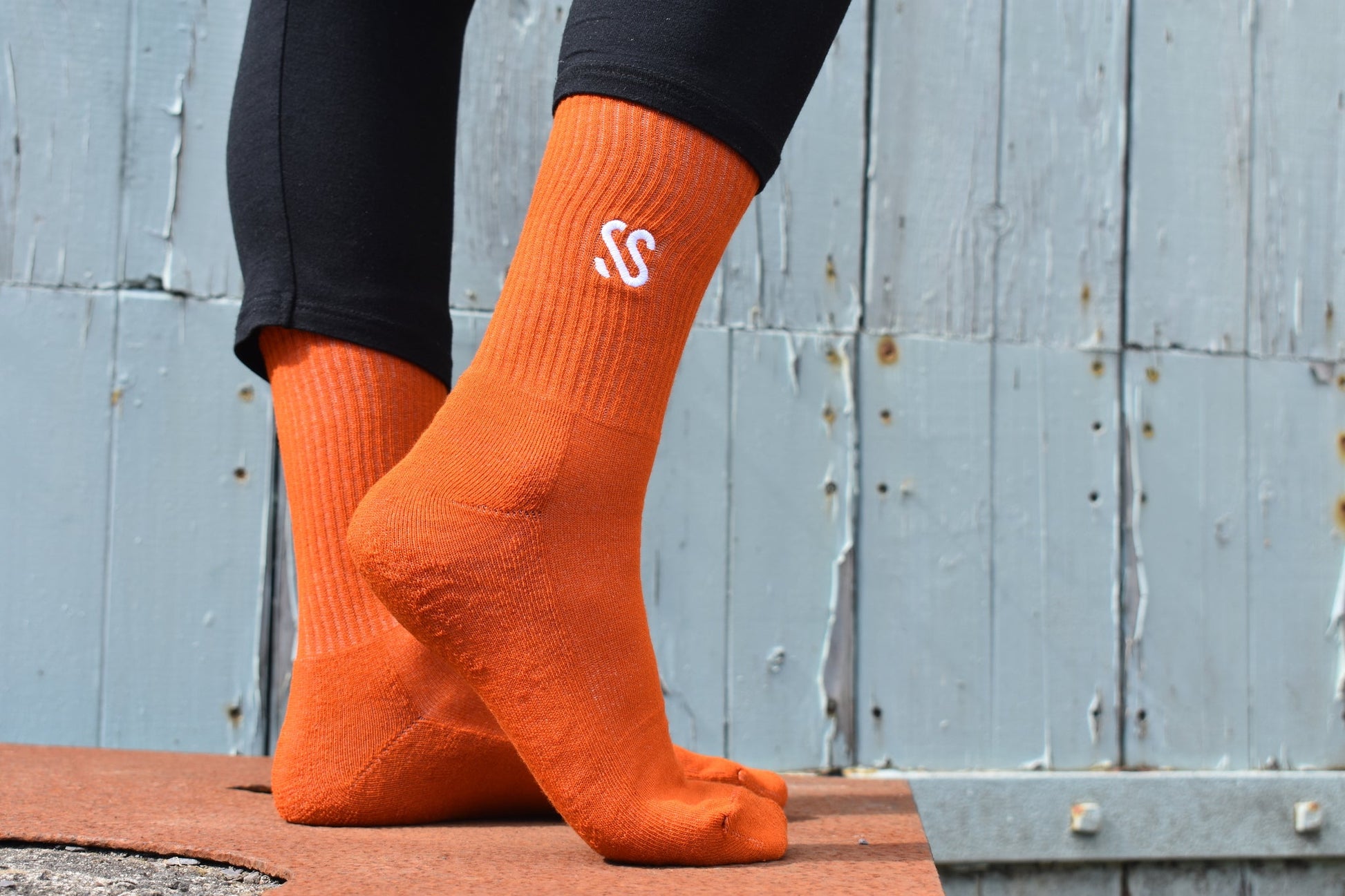 A pair of dark orange combed cotton socks being worn outside